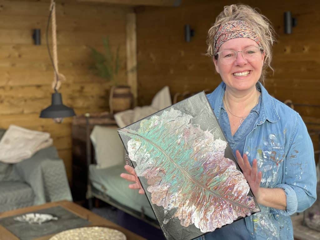 Vrouw met kleurrijk kunstwerk tijdens creatieve workshop bij Vivent Langer Thuis.