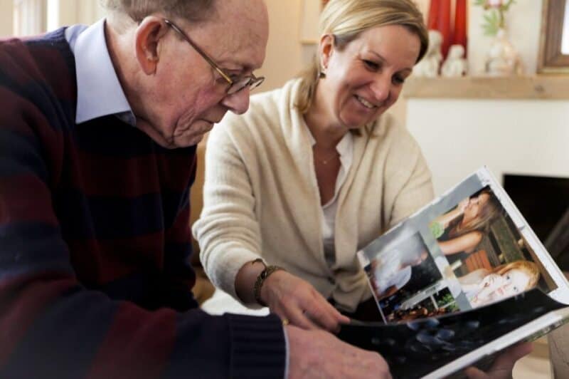 Oudere man en vrouw bekijken fotoalbum samen thuis.