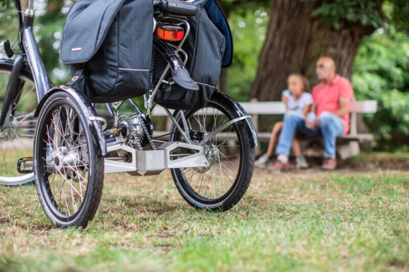 Rolstoel voor ouderen in park met kinderen op achtergrond.